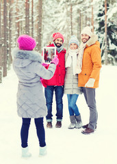 smiling friends with tablet pc in winter forest