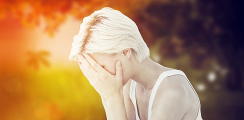 Composite image of sad blonde woman crying with head on hands 
