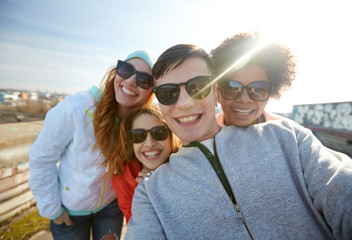 group of happy friends taking selfie on street