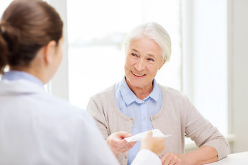 doctor giving prescription to senior woman