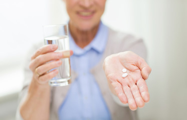 close up of senior woman with water and pills