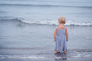 Fototapeta na wymiar Small pretty baby girl walking along seashore