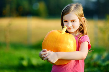 Fototapeta premium Cute little girl holding a pumpkin