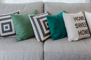 row of green and white pillows on grey sofa