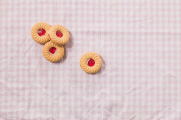 Sweet biscuit with strawberry jam at top on pink tablecloth back