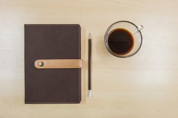 Obraz na płótnie Canvas Brown note book , pencil and black coffee in work concept