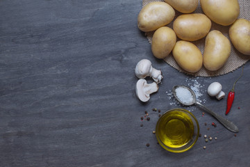 Potatoes, mushrooms and condiment on dark wooden table