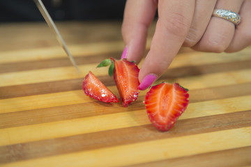Unrecognizable woman cutting strawberry.