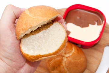 Hand holding donut for topping with chocolate cream