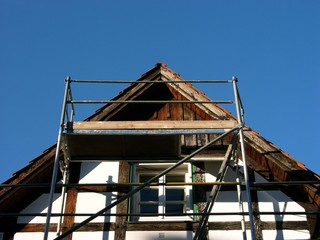 Sanierung der Fachwerkfassade eines denkmalgeschützten Haus vor blauem Himmel bei Sonnenschein in...