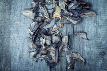 Pieces of dried porcini mushrooms on old gray wooden board. Tone