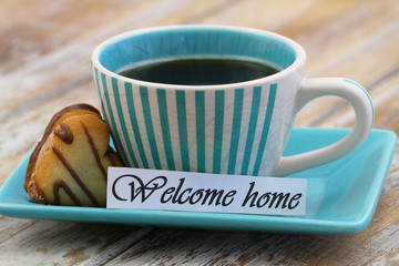 Welcome home card with cup of black coffee and heart shaped biscuit

