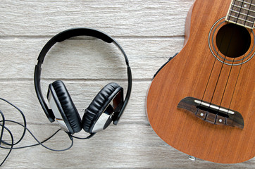 headphone and ukulele guitar on white wooden table