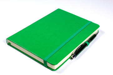 Green notebook and a pen isolated on white