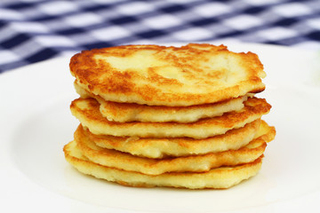 Potato fritters stacked up on white plate
