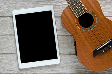 Fototapeta premium tablet and ukulele guitar on white wooden table