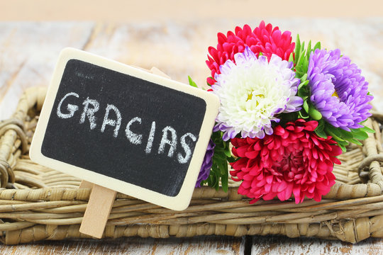 Gracias (which means thank you in Spanish) written on miniature blackboard and colorful aster flower bouquet
