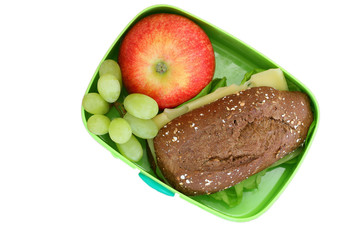 Lunch box containing brown cheese roll, red apple and grapes isolated on white
