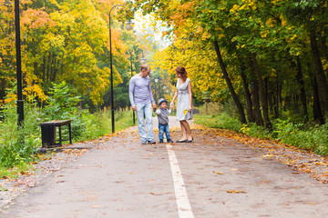 Fototapeta premium Young family for a walk in the autumn park with baby