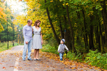 Fototapeta premium Young family for a walk in the autumn park with baby