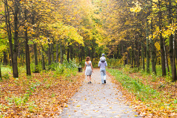 Young family for a walk in the autumn park with baby