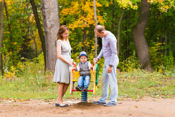 Fototapeta premium Young family for a walk in the autumn park with baby
