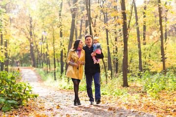 Young family for a walk in the autumn park with baby