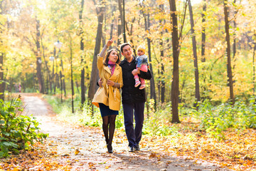Fototapeta premium Young family for a walk in the autumn park with baby