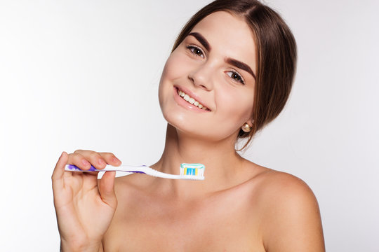 Smiling girl is holding brush with toothpaste isolated on white 
