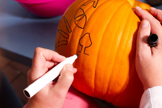 Frau zeichnet auf einem K&uuml;rbis, um aus dem K&uuml;rbis Jack-O-Lantern schnitzen