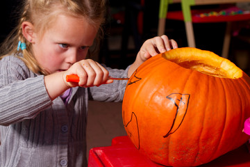 konzentriertes Kind beim bauen eine Kürbis Laterne für Halloween