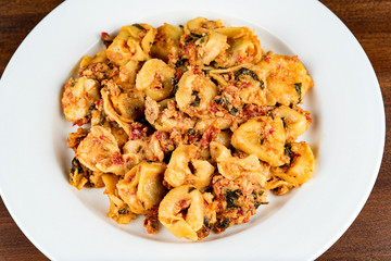 Italian pasta on a white plate on a wooden table. Shallow depth of field. 