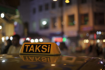Letrero de taxi con luces nocturnas al fondo