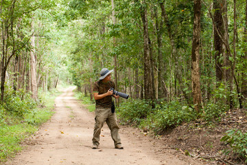 Naklejka premium Adventure photographer, a camouflage adventure guy with camera traveling in the tropical forest,Thailand