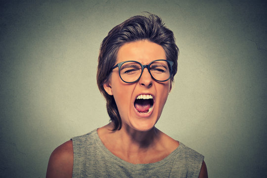 Angry young woman with glasses screaming