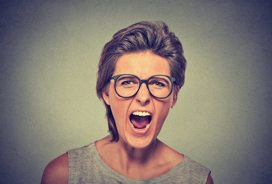 Angry young woman with glasses screaming