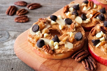Autumn apple rounds with peanut butter, chocolate chips and nuts on a wooden paddle board