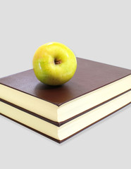 Green apple on stack of book isolated on grey background
