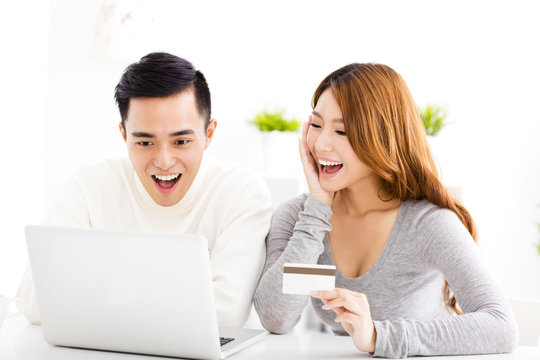 happy young couple with credit card and  laptop