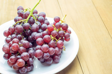 red bunch grape in white dish on wooden board