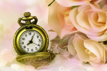 Vintage pocket watch with rose bouquet on pastel tone background