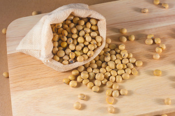 Soybean or yellow bean in sack on wood background