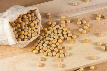Soybean or yellow bean in sack on wood background