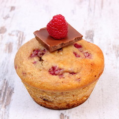 Fresh baked muffins with raspberries and chocolate on wooden background, delicious dessert