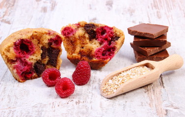 Muffins with raspberries, chocolate and oat bran on spoon, wooden background, delicious dessert