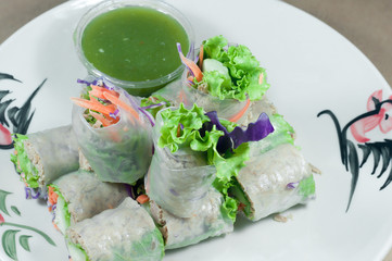 Portion of spring rolls on old wood with spicy sauce, vegetables