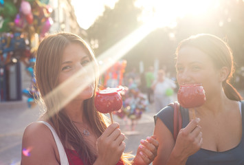 young women eating candy apple and enjoying