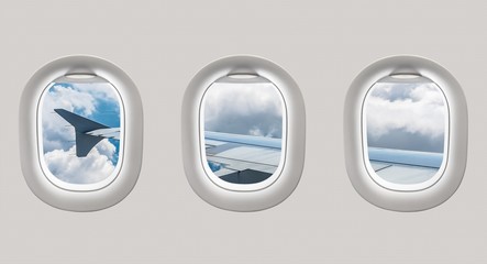 Looking out the windows of a plane to the aircraft wing and clou