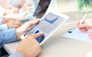 Cropped shot of a group of businesspeople looking at graphs on digital tablets