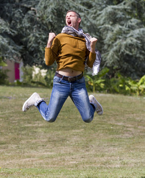 ecstatic young man jumping high for success in sunny park